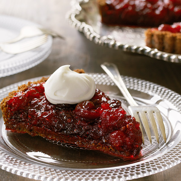 Cranberry ginger tart with a dollop of whipped cream on top.