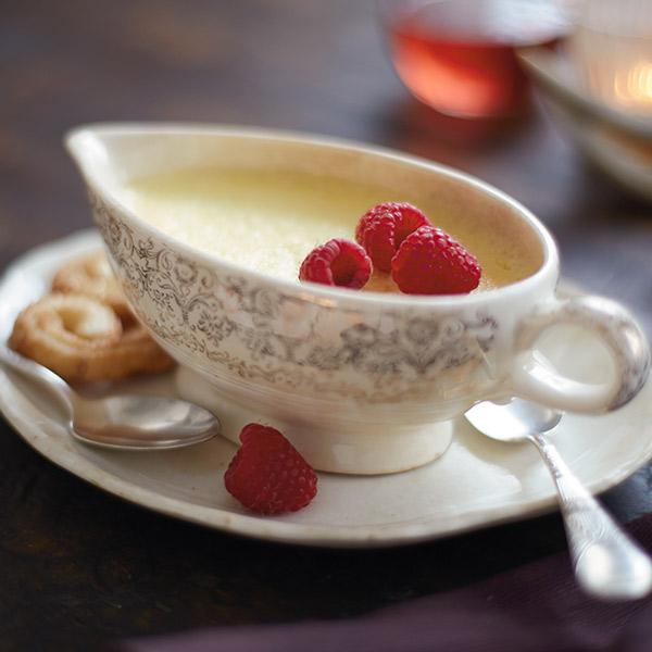 Rich lemon pot de crème garnished with fresh raspberries.