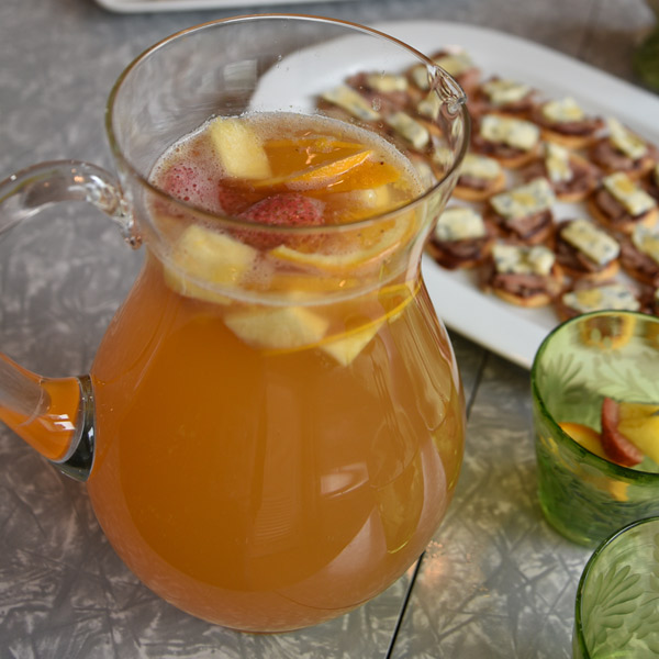 A pitcher of white sangria with chunks of strawberries, pineapple and oranges.