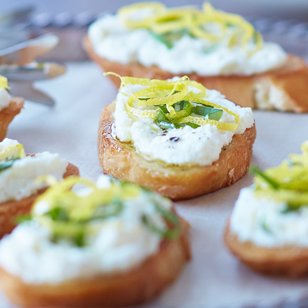 Lemon ricotta bruschetta with creamy ricotta, lemon zest and basil garnish.