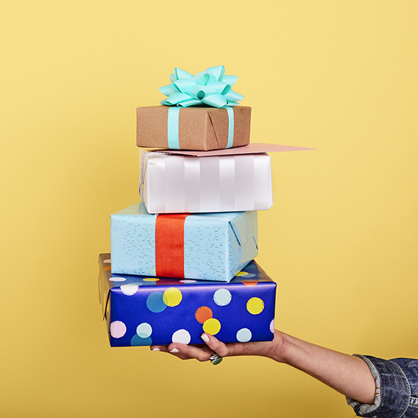 Hand holding four presents stacked with a card