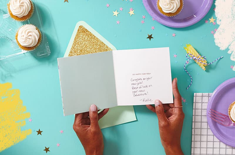 Hands holding a greeting card with handwritten message inside that reads,