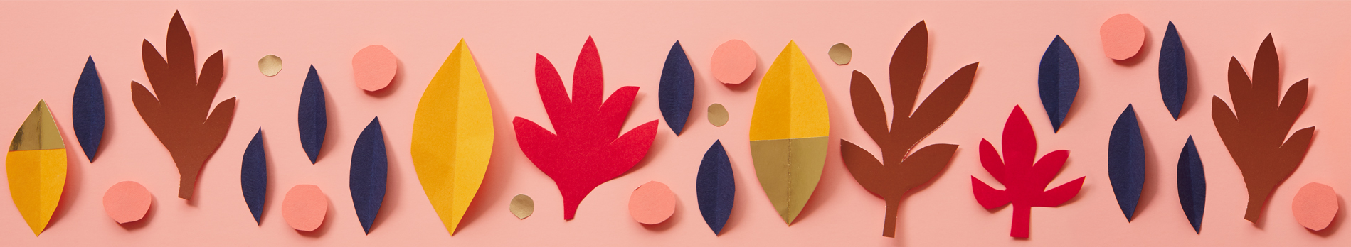 Fall background with paper cut leaves on a pink surface