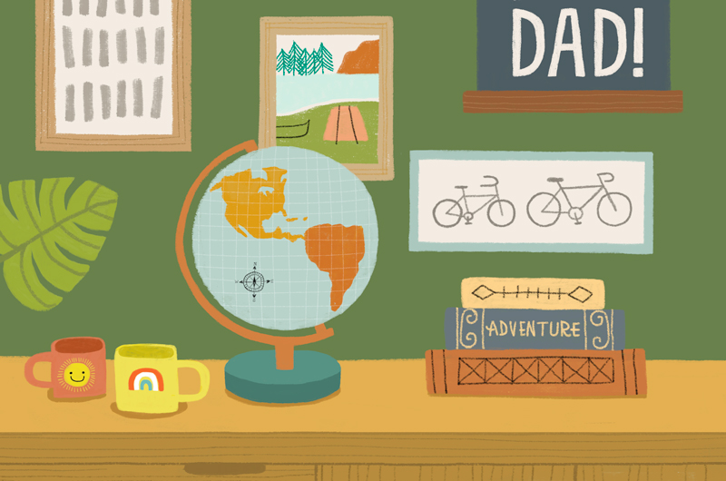 A home office desk with a stack of books, a globe and two mugs sitting on it; on the wall behind the desk hang pictures of bicycles, a campground and a plaque that reads