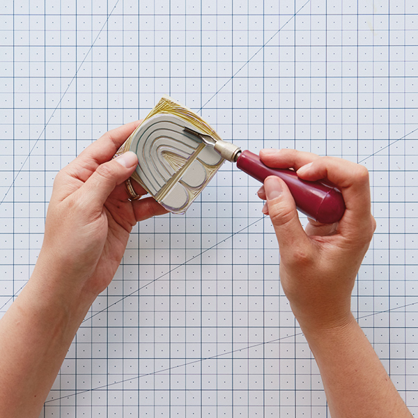 Hands carving out a design on a rubber stamp.