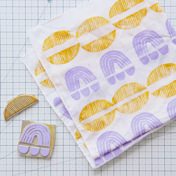 A finished hand-stamped tea towel with the rubber stamps carved to create it sitting nearby.