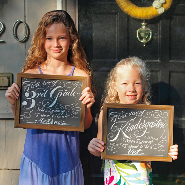 Designer Josh S.'s two little girls holding back-school-signs for the first day of third grade and kindergarten, respectively.