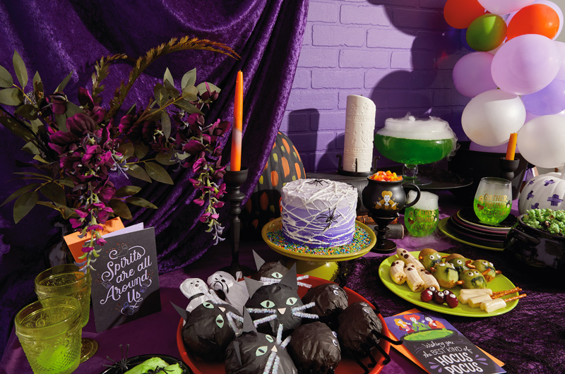 A Hocus Pocus-themed party table set with a variety of snacks, treats, party favors and decorations.