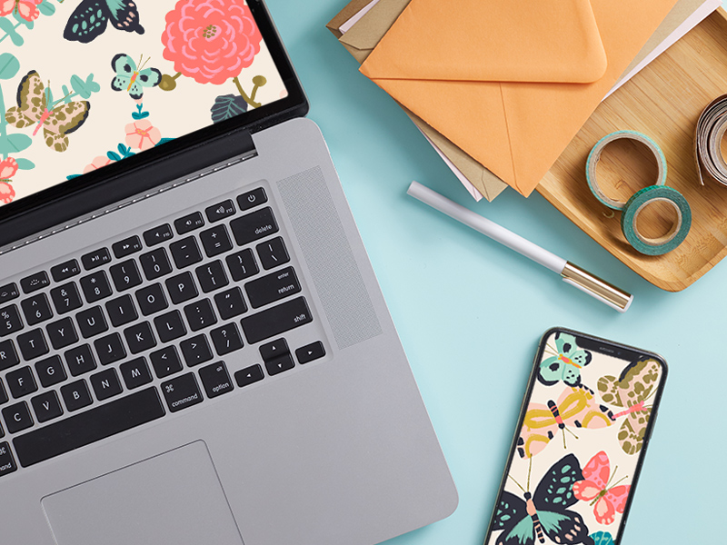 A laptop screen displaying the free April downloadable desktop wallpaper, with a mobile phone displaying the free downloadable mobile wallpaper lying nearby.