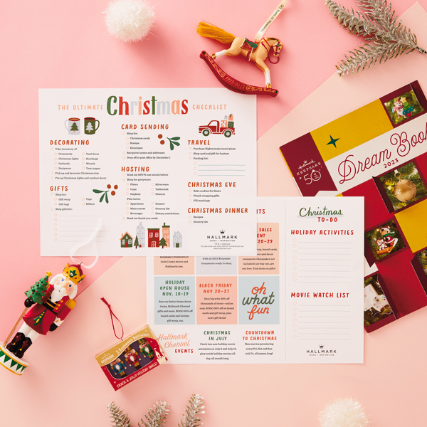 Our free, printable, ultimate Christmas to-do list lying on a light pink surface, surrounded by silver tinsel and Hallmark Keepsake Ornaments.
